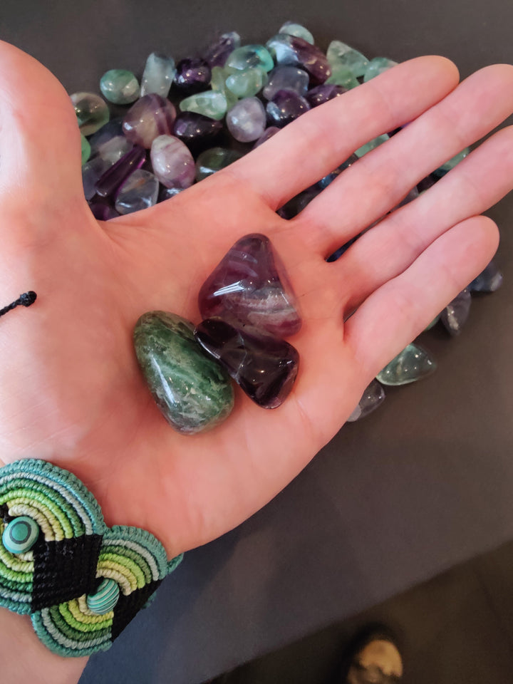 Tumbled fluorite stones in open palm with multicolor pieces around
