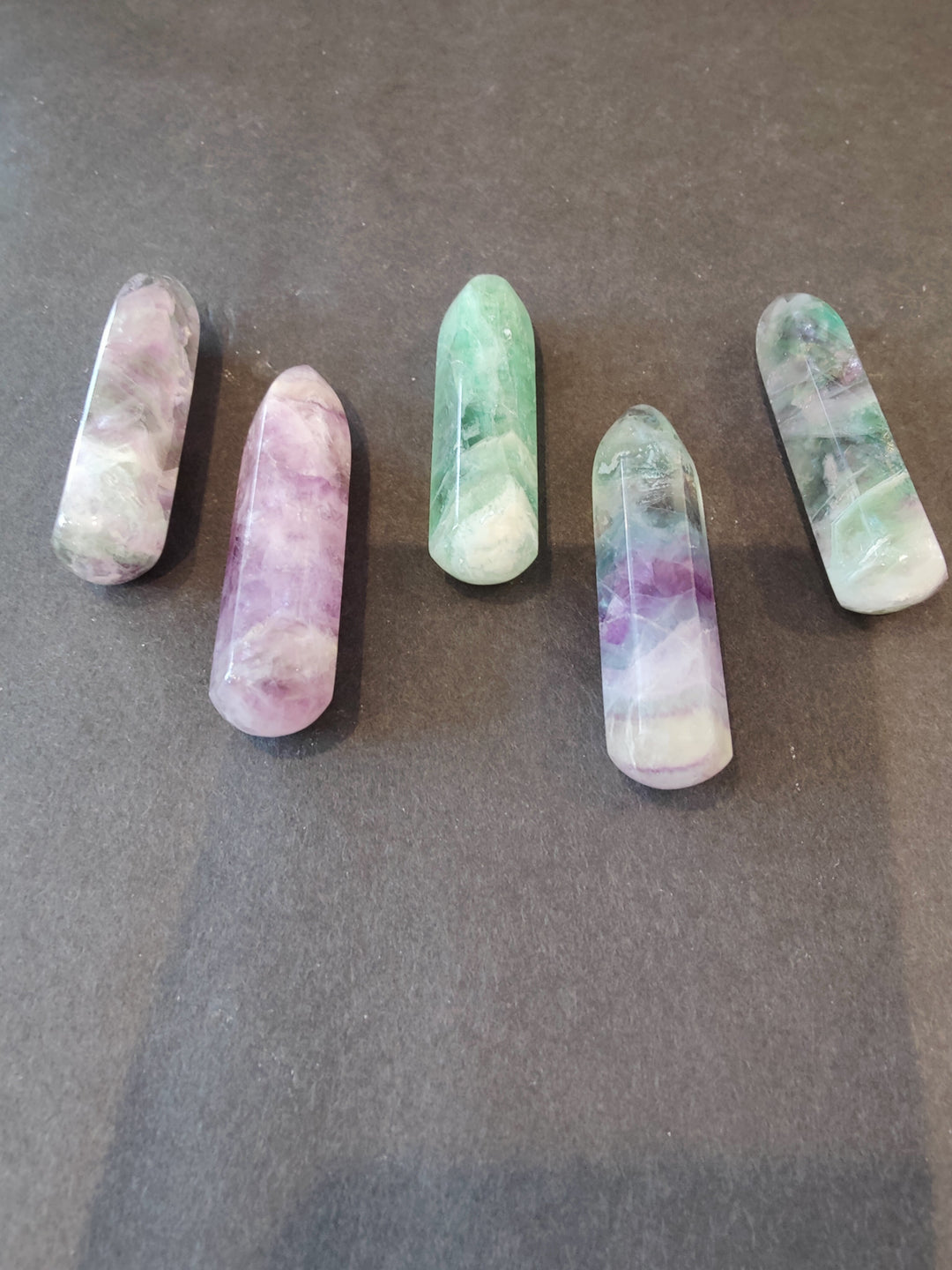 Fluorite crystal points with pastel banding, elongated obelisk shapes in green, purple, and white