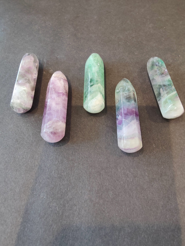 Fluorite crystal points with pastel banding, elongated obelisk shapes in green, purple, and white