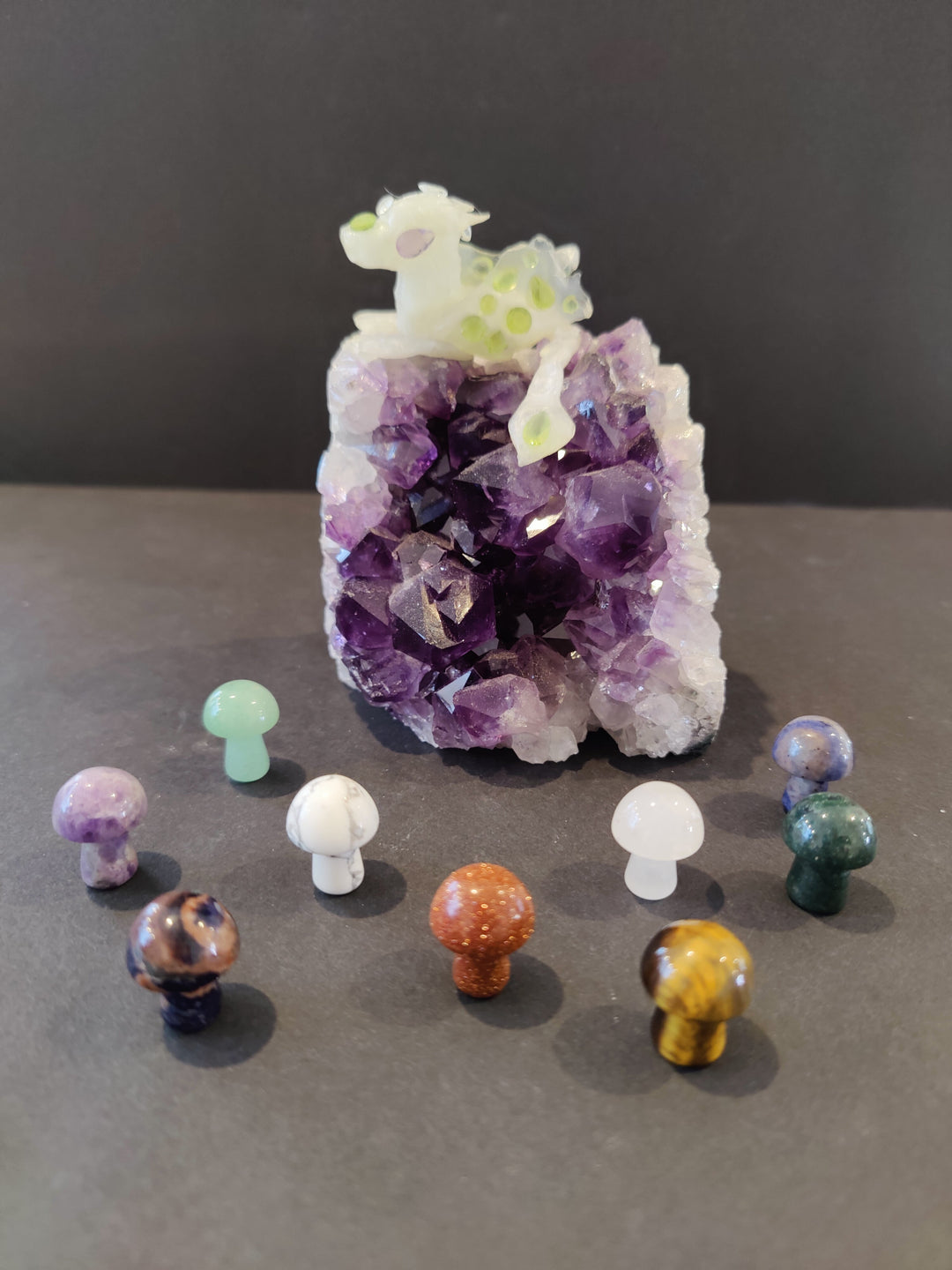 Amethyst-style mushroom stone sculpture with pale top, surrounded by small crystal stones.