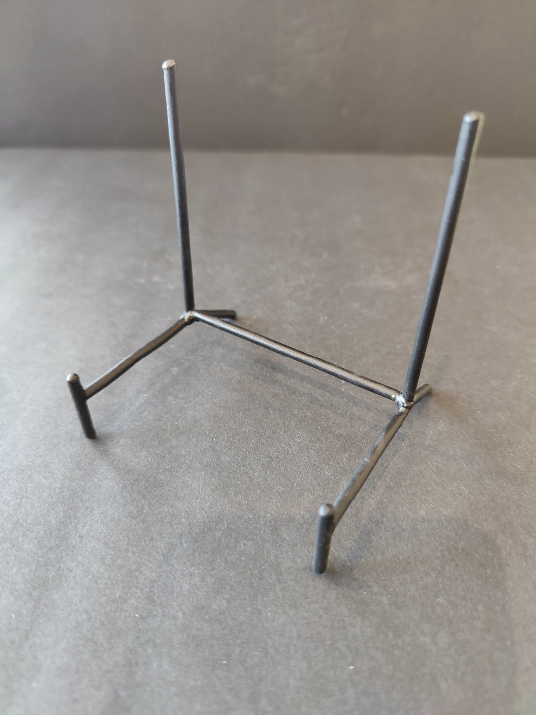 Black wrought iron display stand with three legs and two upright posts