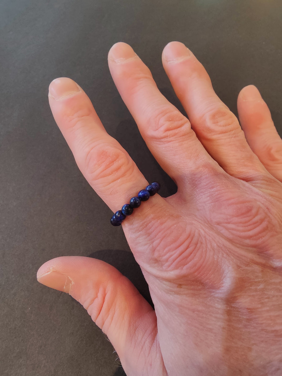 Beaded stone ring with dark blue 4mm beads on a hand.