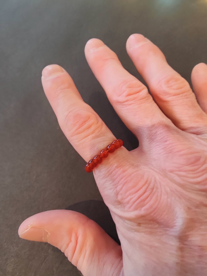 Beaded stone ring with red 4mm beads on a hand.