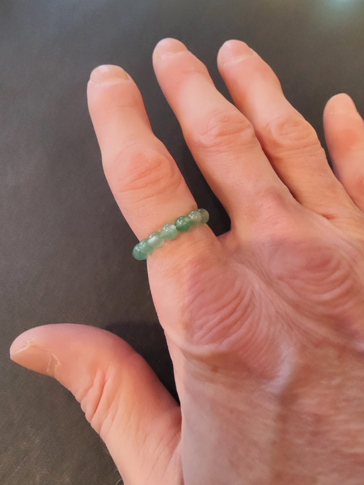 Beaded stone ring with light green 4mm beads on a hand.