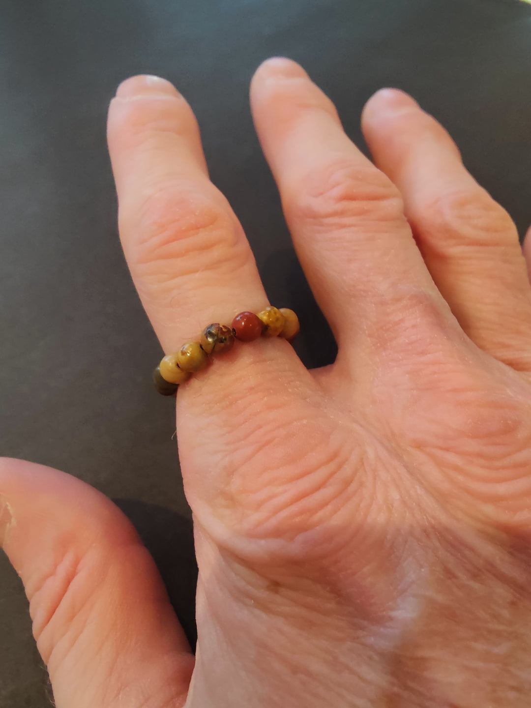 Beaded stone ring with amber and brown 4mm beads on a hand.