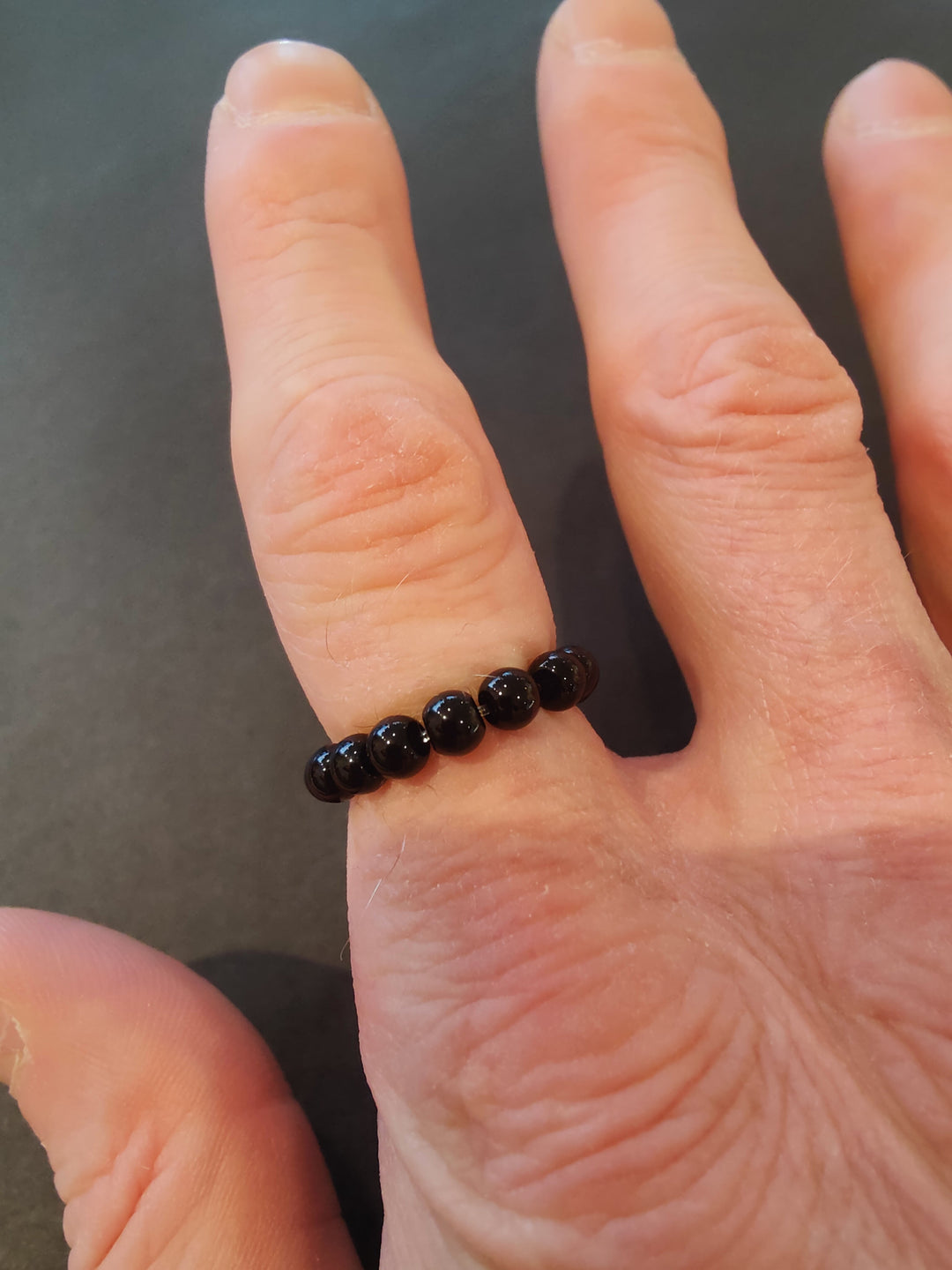 Beaded stone ring with black 4mm beads on a hand.