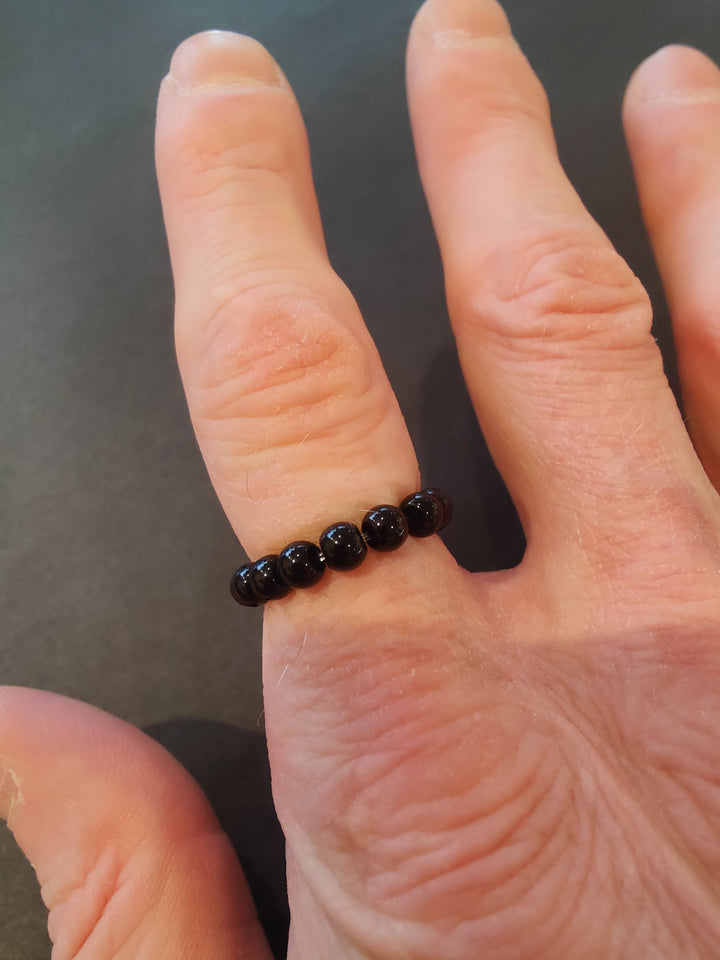 Beaded stone ring with black 4mm beads on a hand.