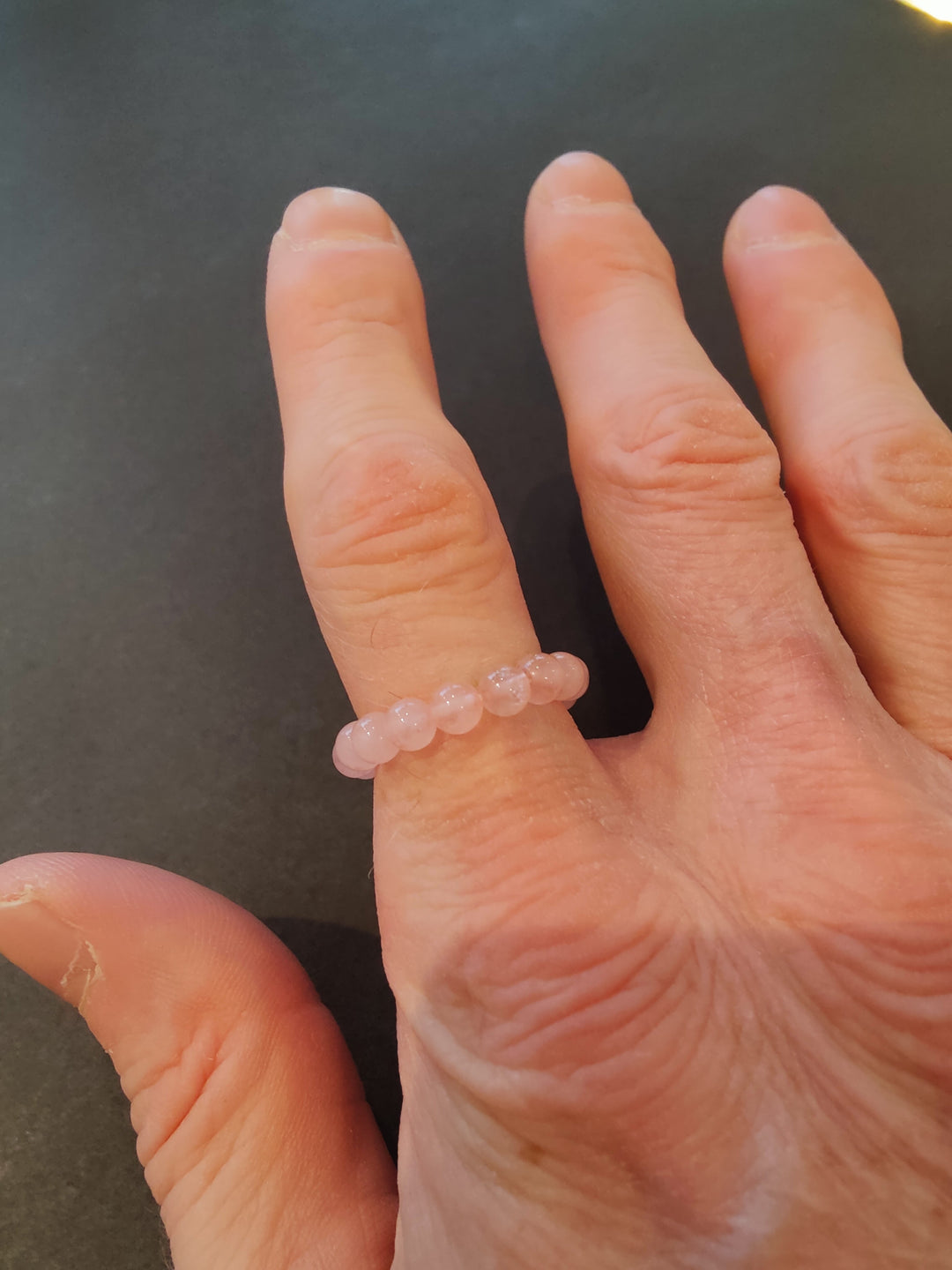 Beaded stone ring with pale pink 4mm beads on a hand.