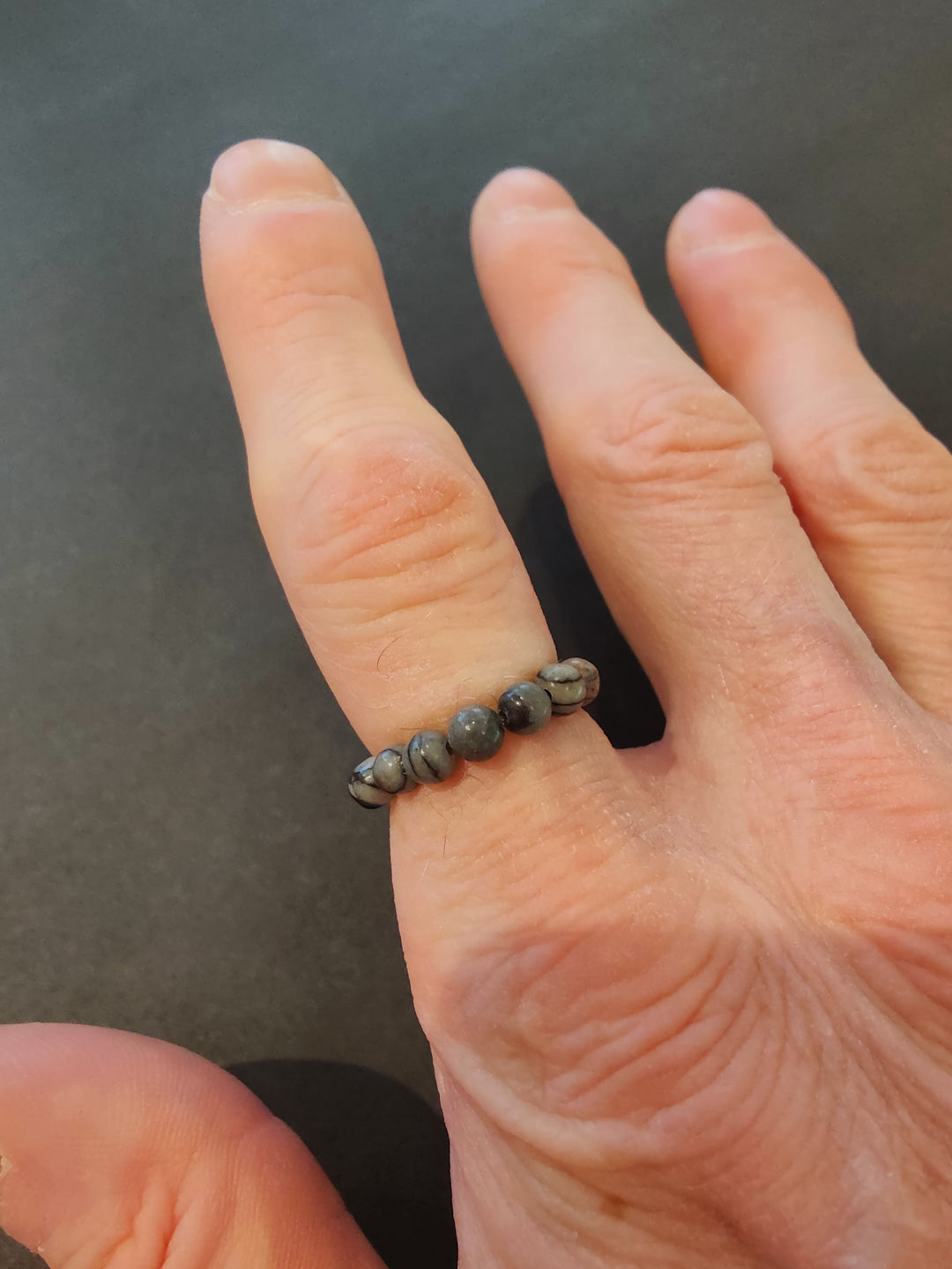 Beaded stone ring with gray 4mm beads on a hand.