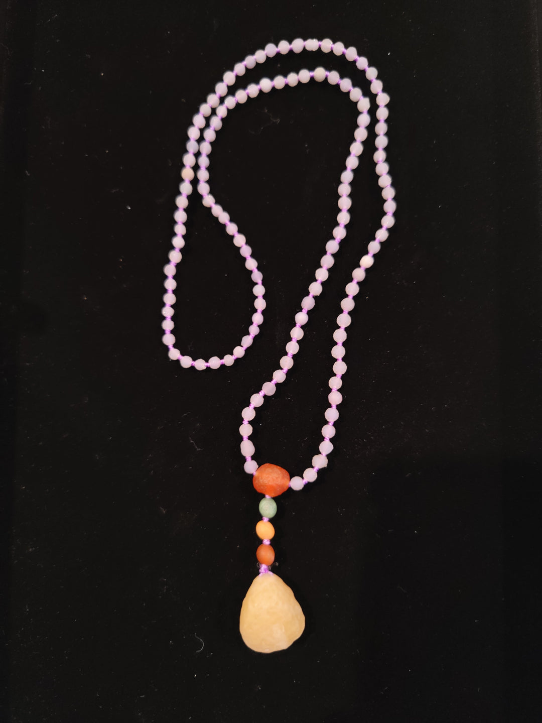 Pink bead necklace with layered strands and teardrop stone pendant