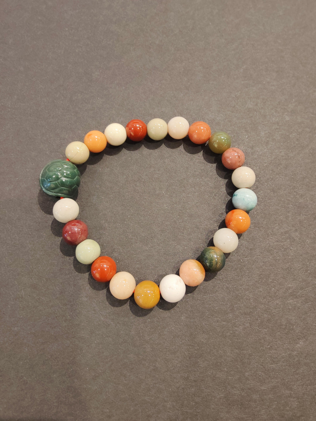 Multi-color bead bracelet with large green animal charm