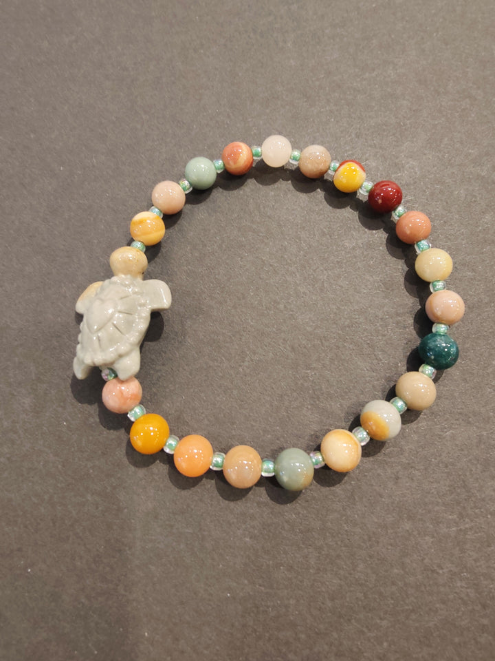 Multi-color bead bracelet with light-colored animal figurine charm