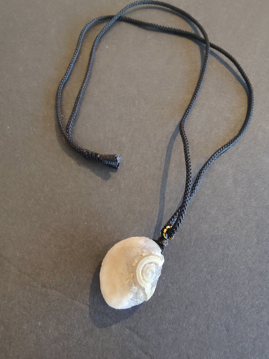 Eye agate pendant necklace with tan-and-white spiral stone on dark cord
