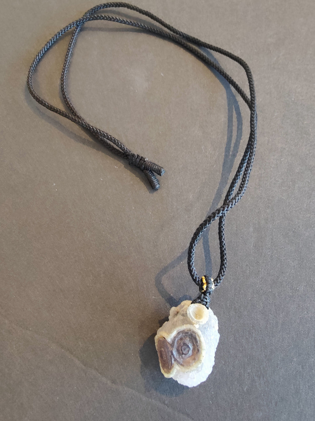 Eye agate pendant necklace with round purple-and-white stone on dark cord