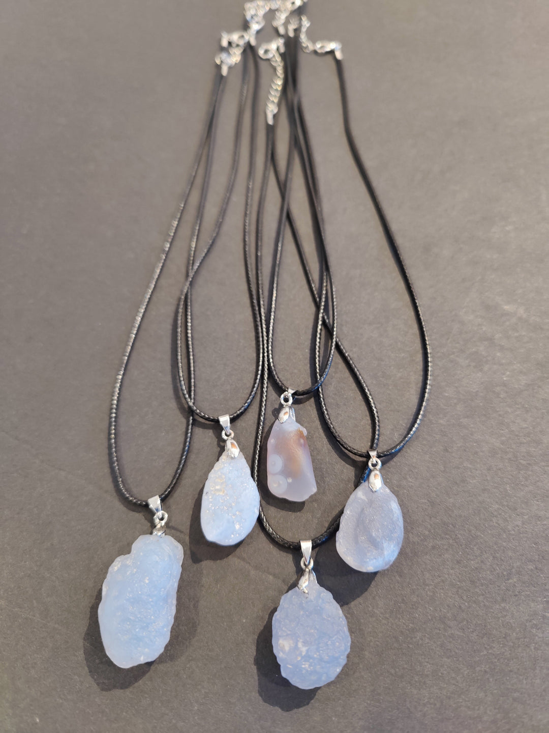 Blue raw stone pendant necklace on gray cord, multiple teardrop-shaped stones