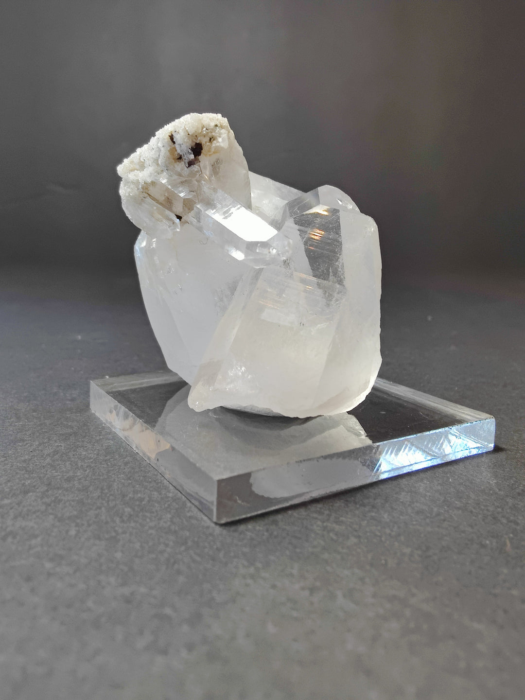 Quartz point crystal cluster on clear base; translucent white stones with dark specks