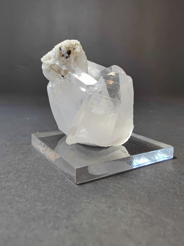 Quartz point crystal cluster on clear base; translucent white stones with dark specks