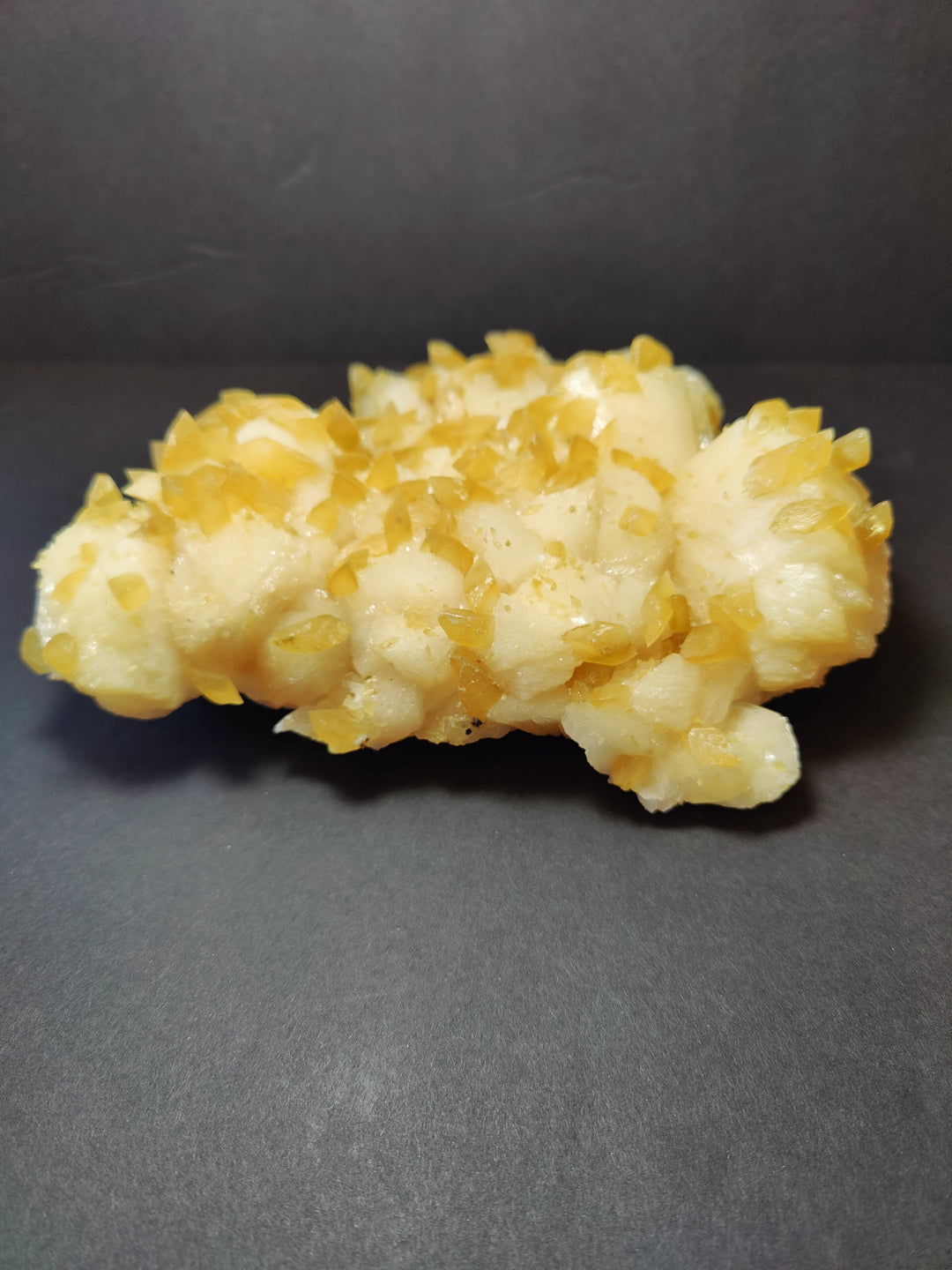 Golden calcite crystal cluster, dense yellow crystals over off-white stone
