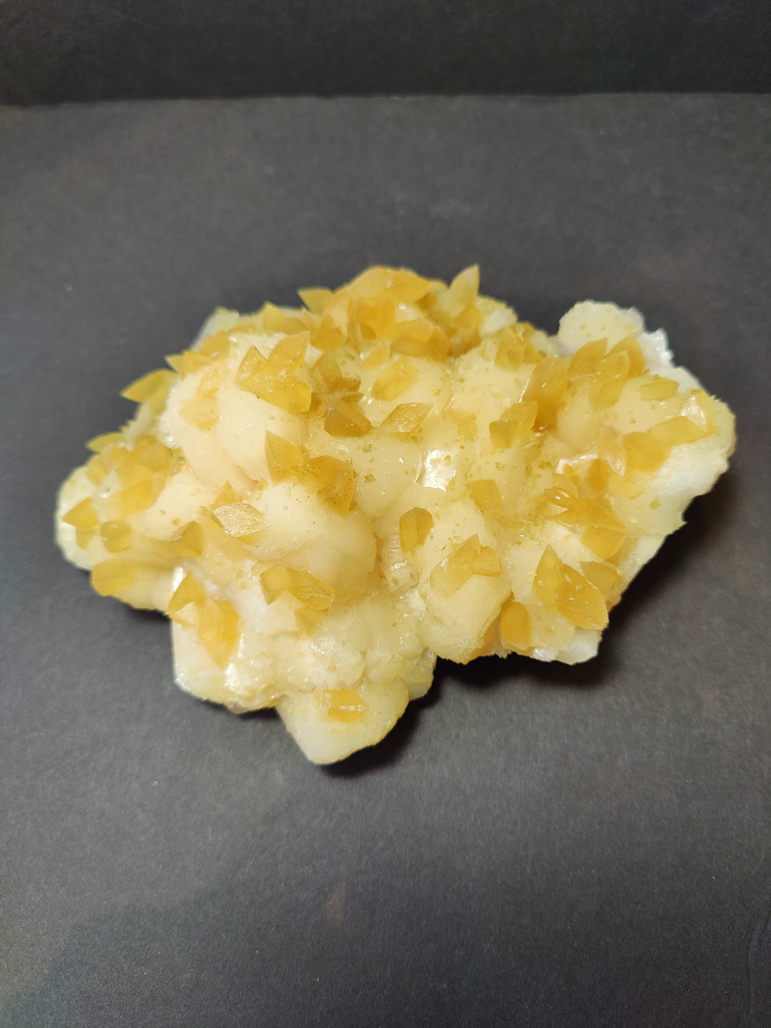 Golden calcite crystal cluster with yellow crystal points on pale base