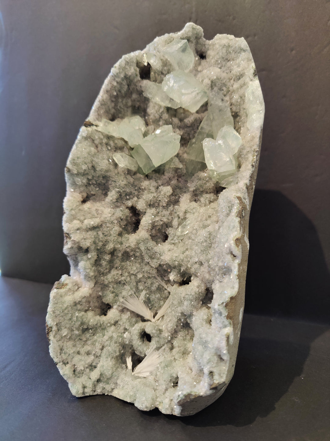 Apophyllite crystal specimen with clusters of pale green crystals on gray matrix