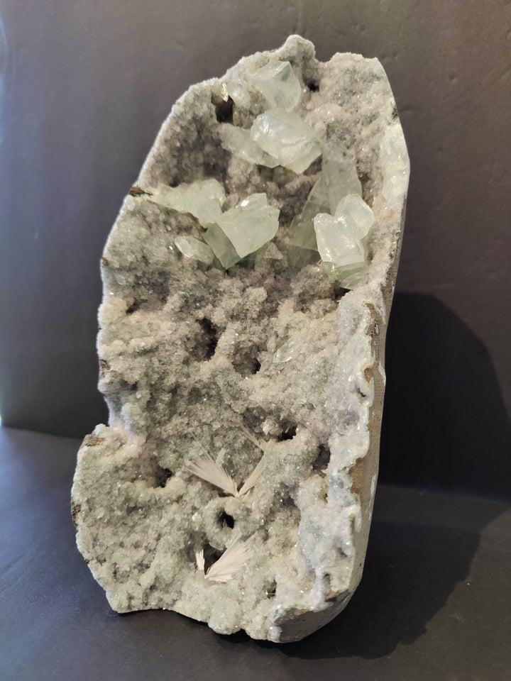 Apophyllite crystal specimen with clusters of pale green crystals on gray matrix