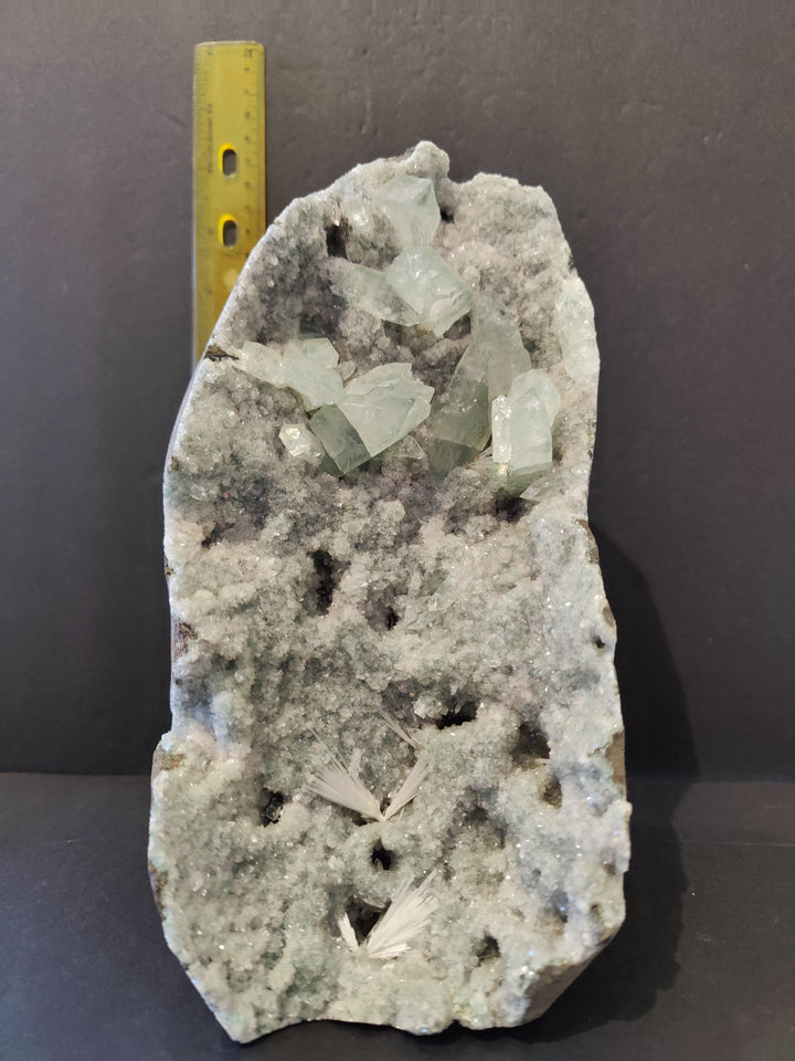 Apophyllite crystal specimen with pale green crystals beside yellow measurement ruler