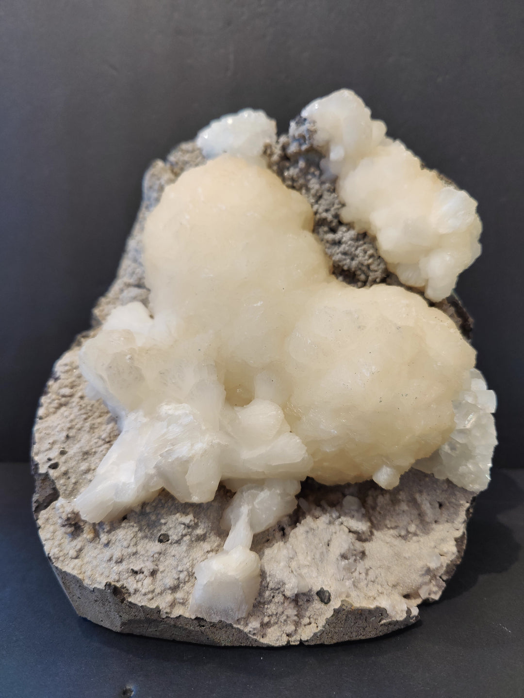 Heart-shaped mineral specimen with pale white crystals on gray rock base