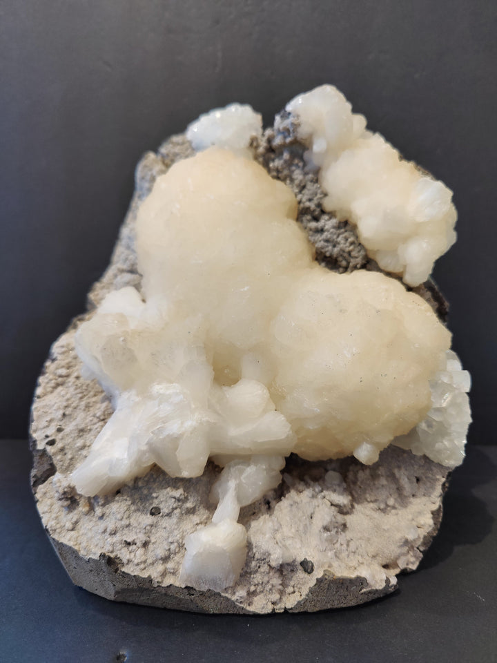 Heart-shaped mineral specimen with pale white crystals on gray rock base
