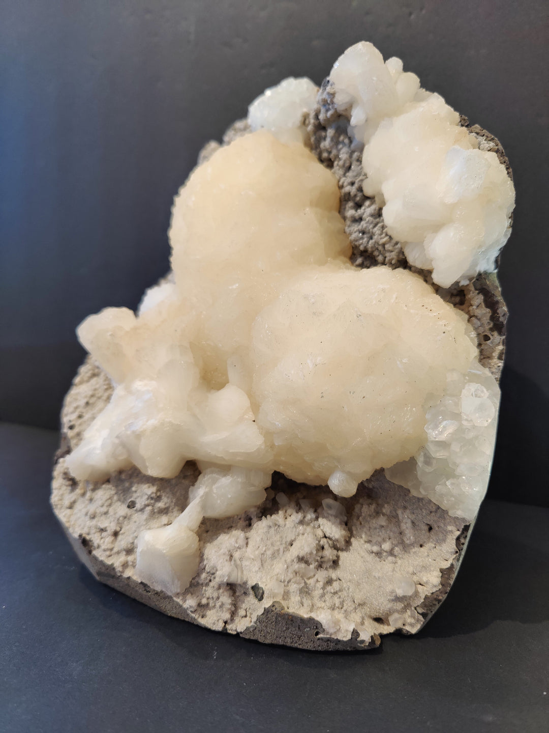 Heart-shaped mineral cluster with white and cream crystals on gray rock