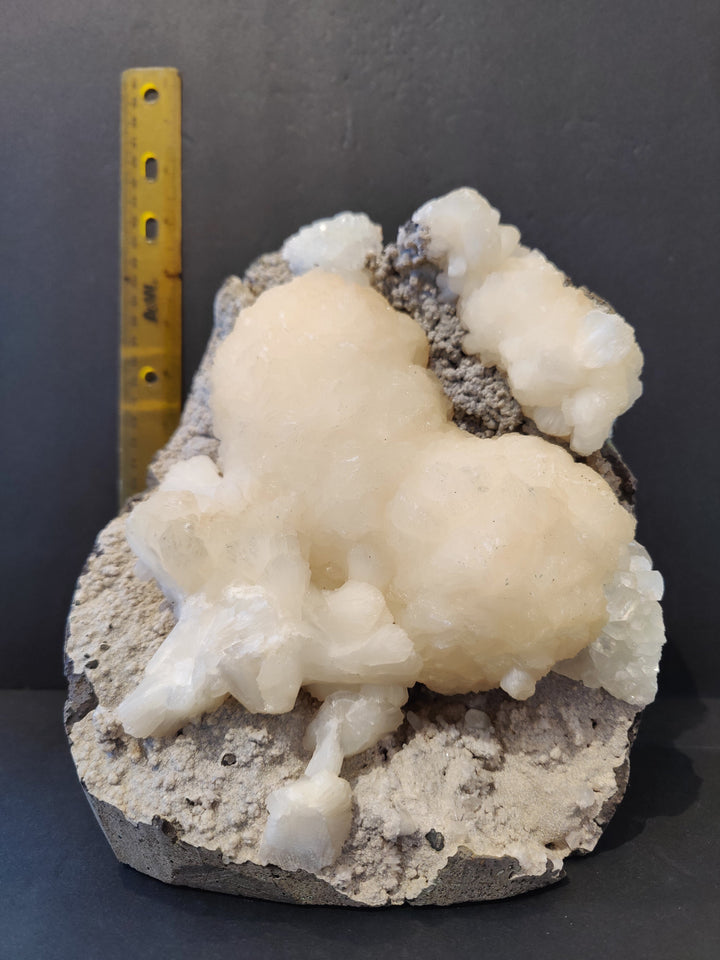 Heart-shaped mineral specimen with crystal clusters and ruler for scale