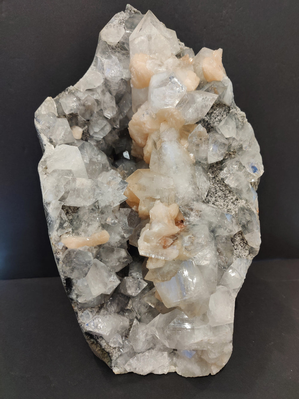 Mineral specimen with clear quartz and peach stilbite crystals, rough gray matrix
