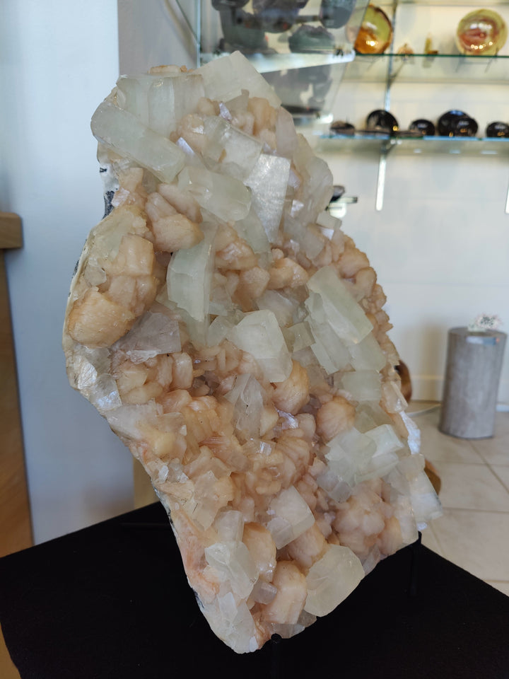 Clear and peach mineral crystal slab specimen on black base, angled view
