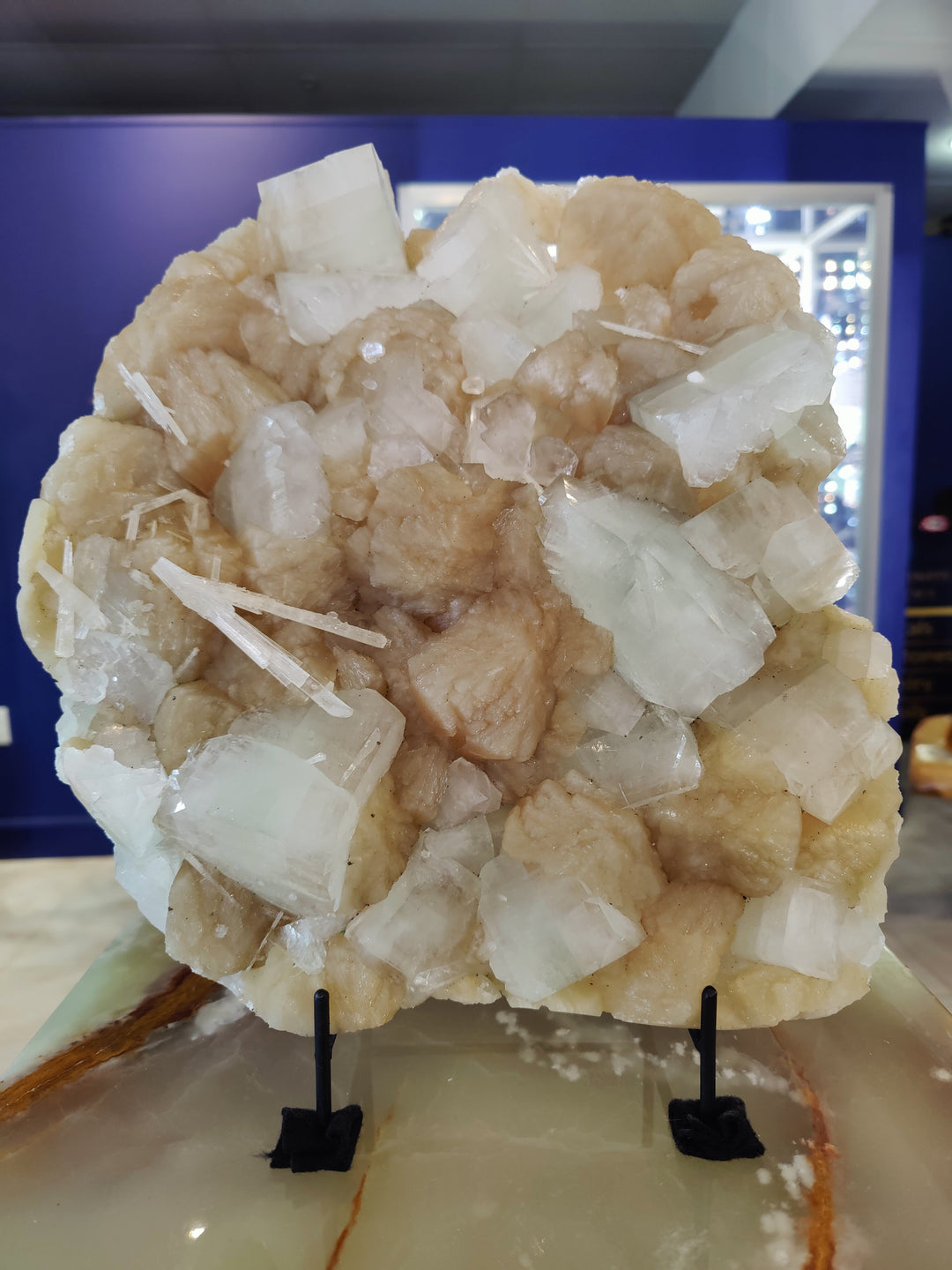 Crystal specimen cluster with clear and pale beige blocky crystals on black stand