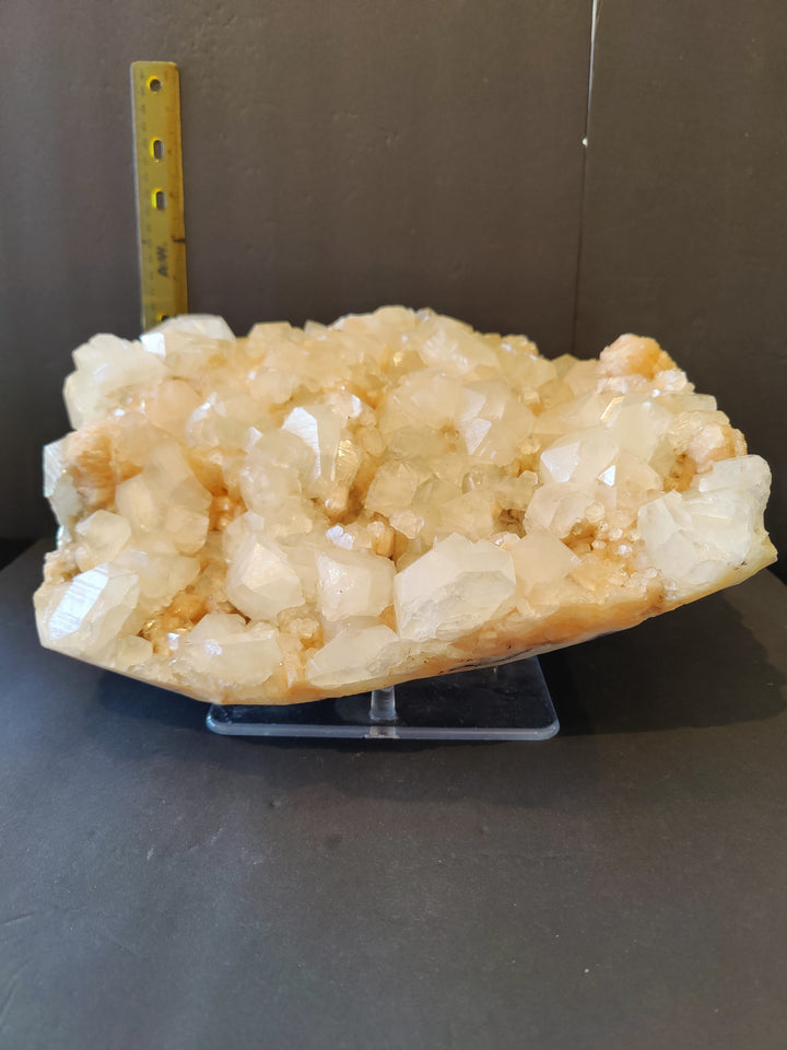 Mineral crystal cluster specimen on blue stand, clear white with peach orange tones