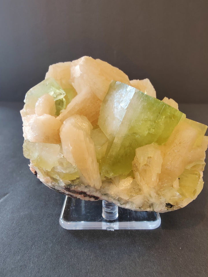 Green and peach crystal cluster with translucent cube faces on clear stand