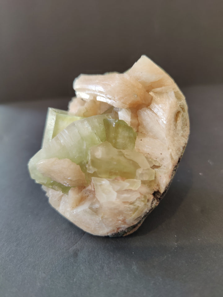 Small mineral specimen with pale peach base and green crystal block clusters
