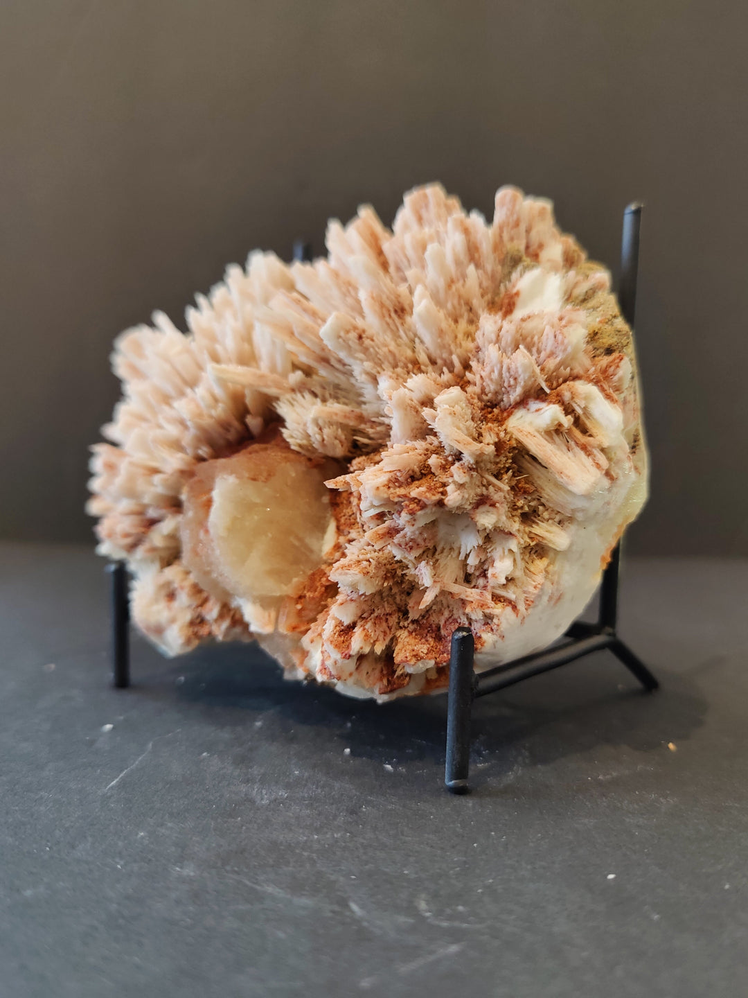 Mineral specimen with beige crystal spikes and light tan core, on black stand