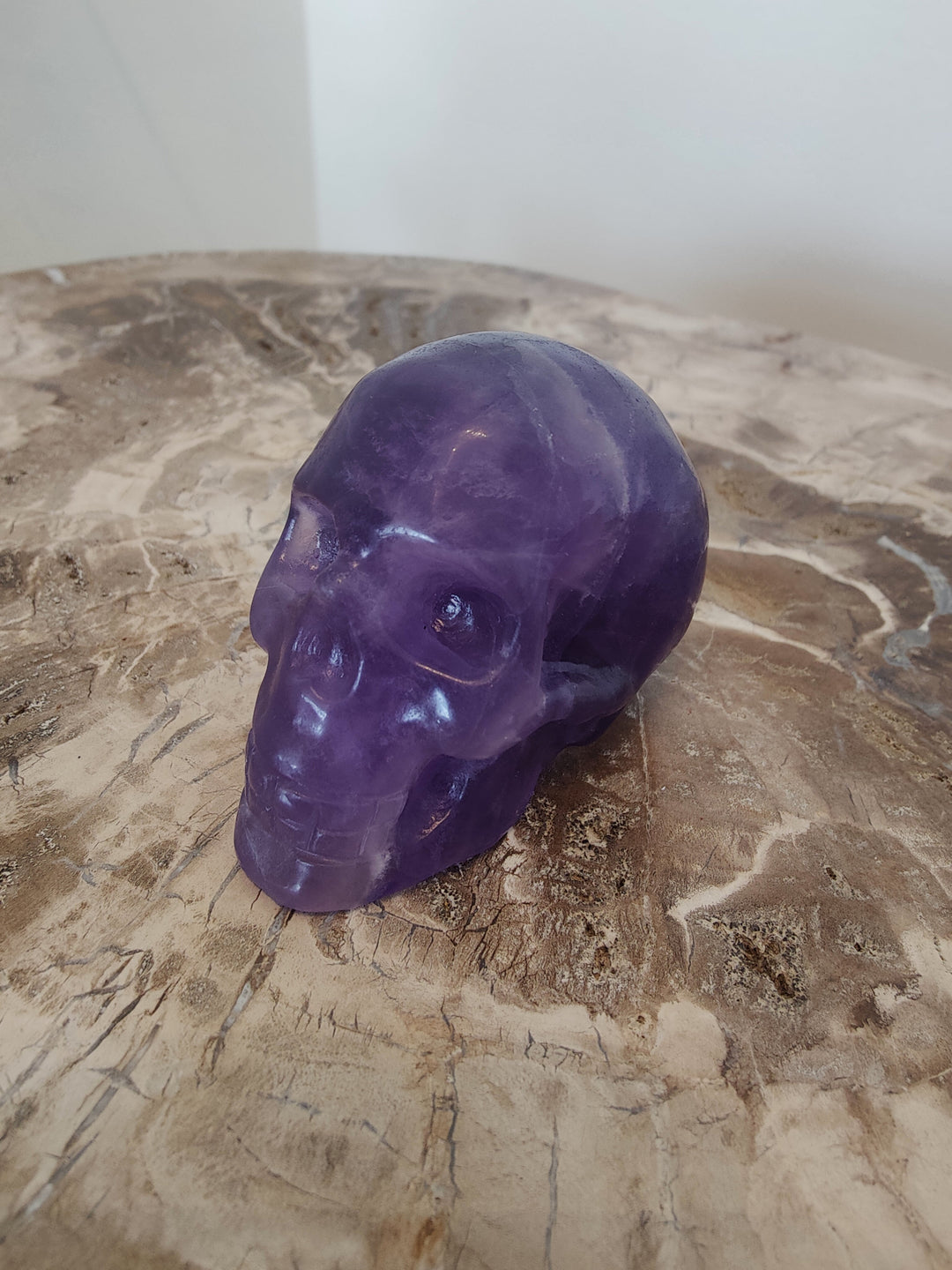 Purple fluorite skull sculpture with carved eyes and nose, glossy polished finish