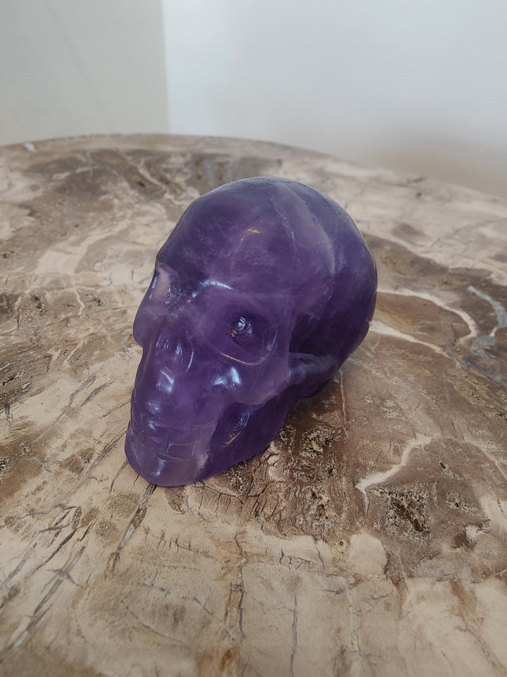 Purple fluorite skull sculpture with carved eyes and nose, glossy polished finish