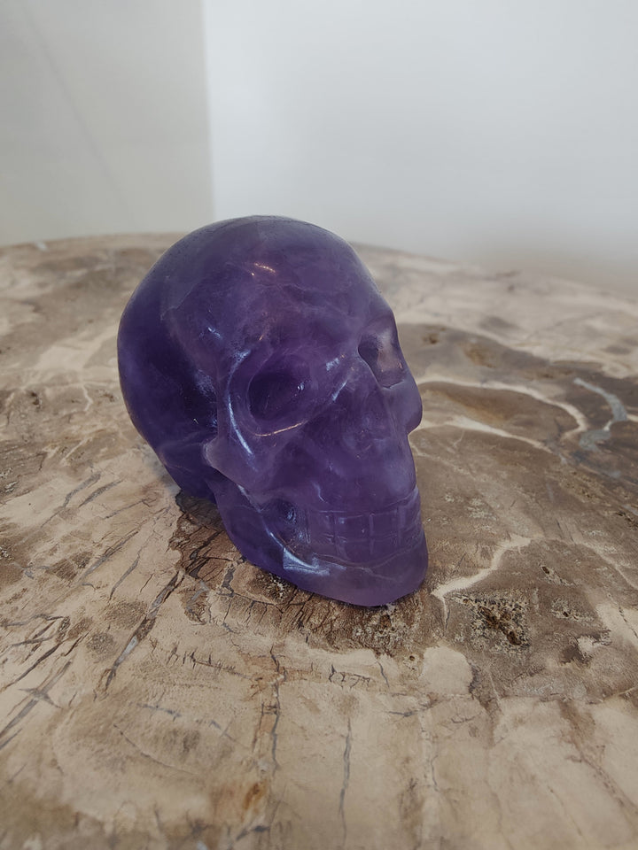 Polished purple fluorite skull sculpture, side view with carved facial features