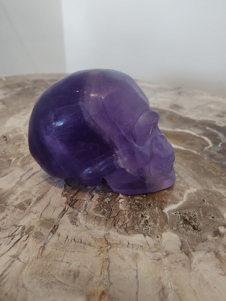 Purple fluorite skull sculpture, angled view with smooth glossy surface