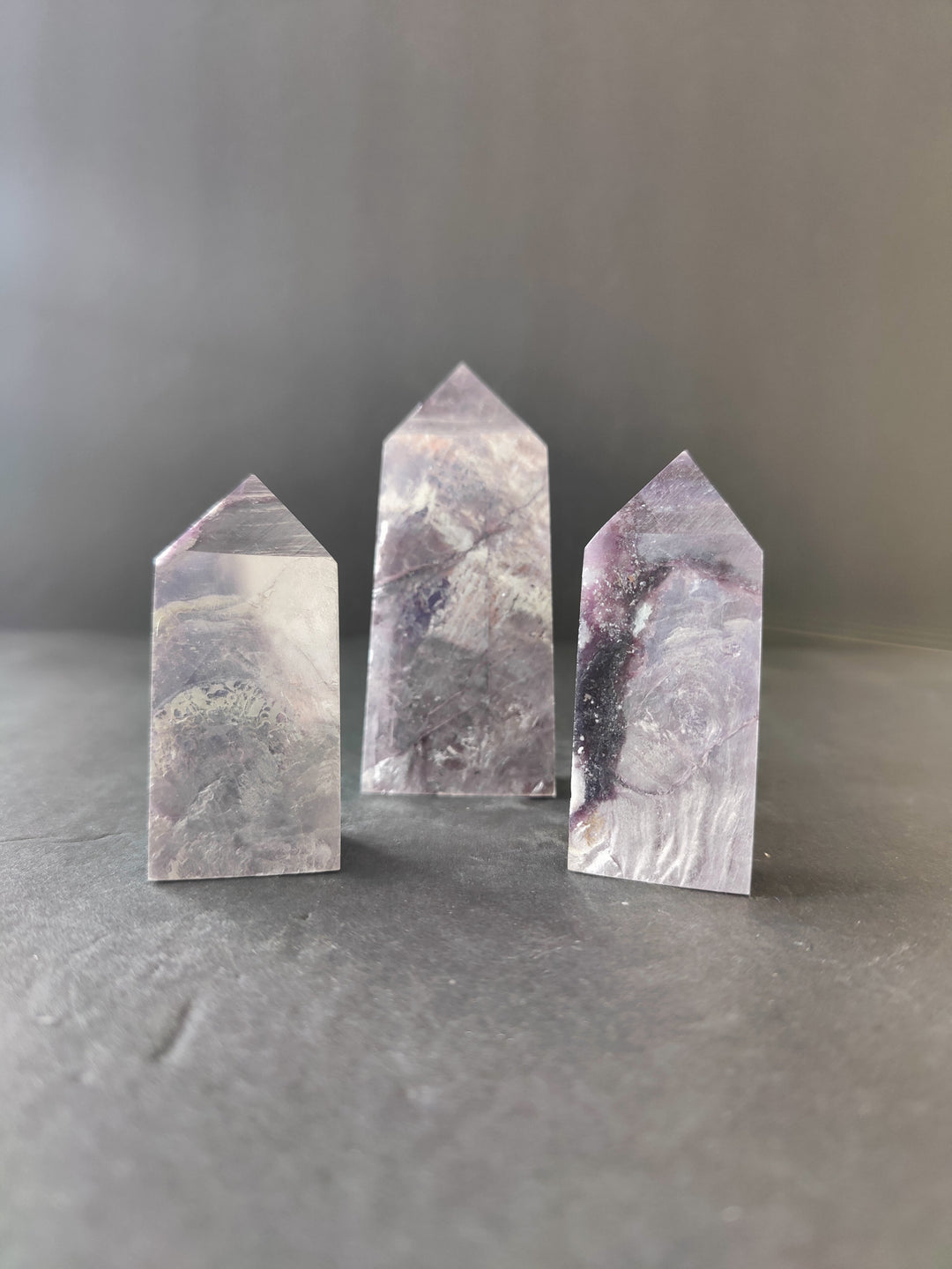 Lepidolite tower sculptures, three polished stone prisms with purple-gray veining