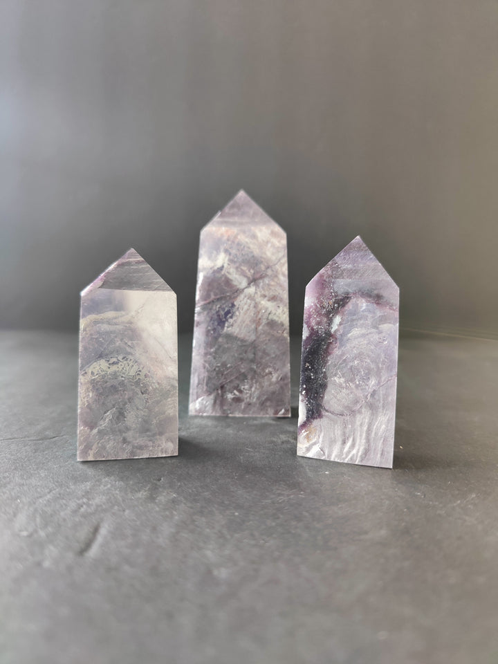 Lepidolite tower sculptures, three polished stone prisms with purple-gray veining