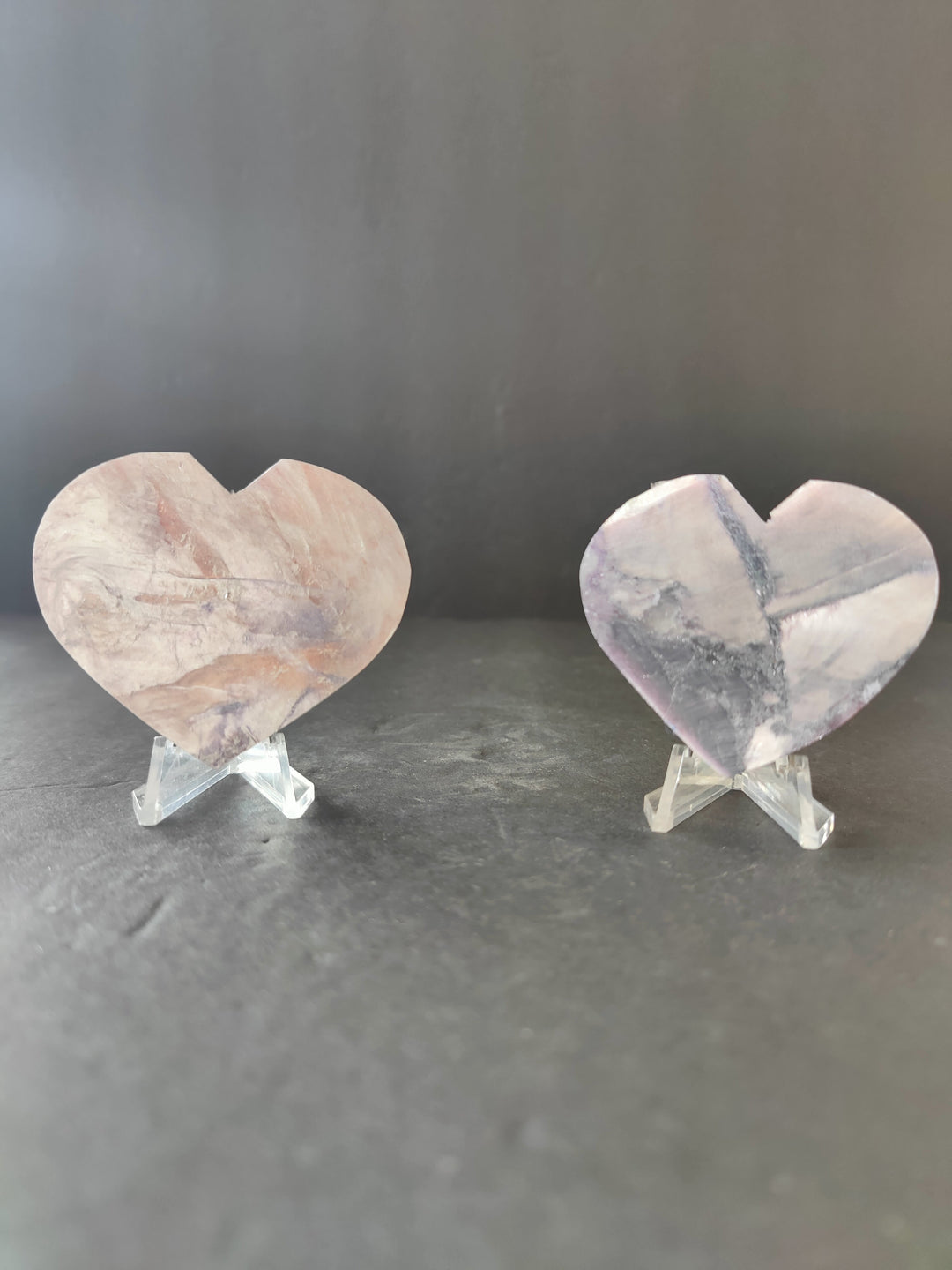 Lepidolite heart sculptures, two polished hearts on clear stands with lilac veining