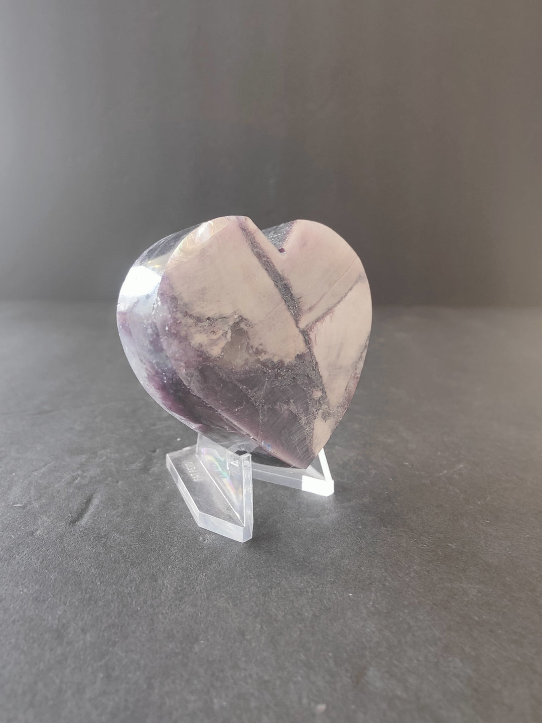 Lepidolite heart sculpture with marbled pale pink, purple, and gray swirls on stand