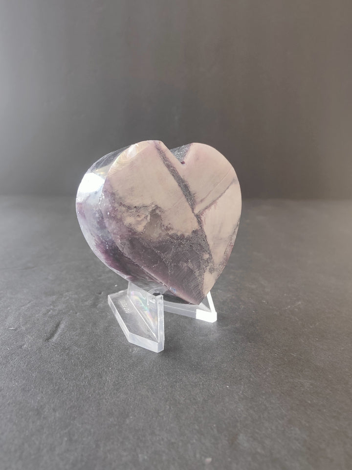 Lepidolite heart sculpture with marbled pale pink, purple, and gray swirls on stand