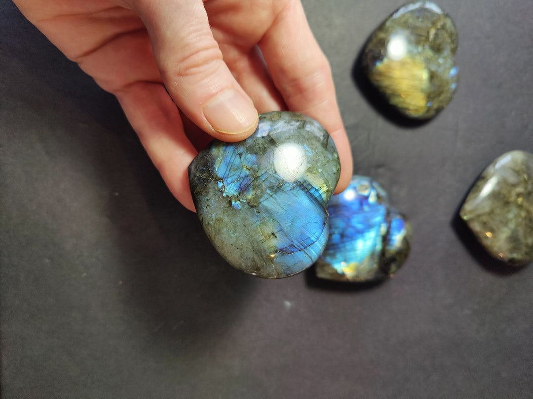 Polished labradorite heart with blue flash and green-gold speckled surface, another heart nearby