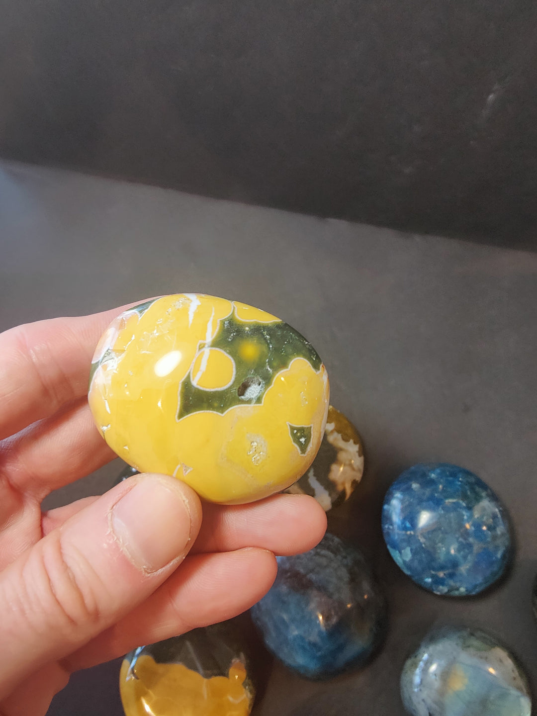 Polished yellow palmstone with white and green markings; rounded oval stone.