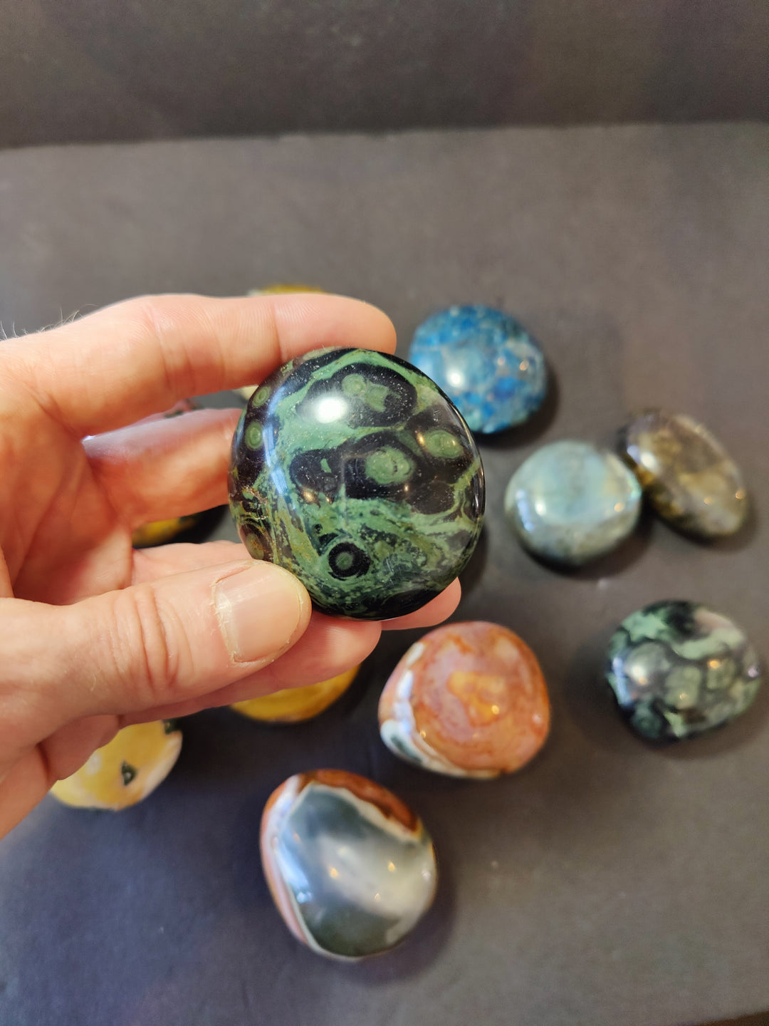 Polished green palmstone with dark swirling patterns; rounded oval stone.