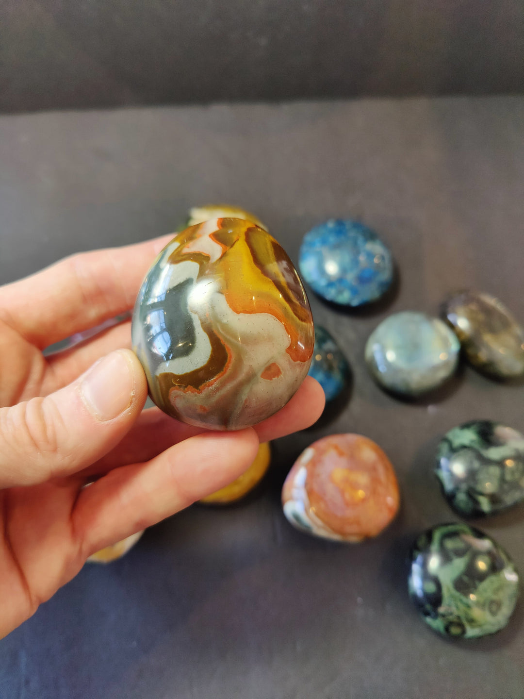 Polished amber-and-cream palmstone with white swirls; smooth rounded oval stone.